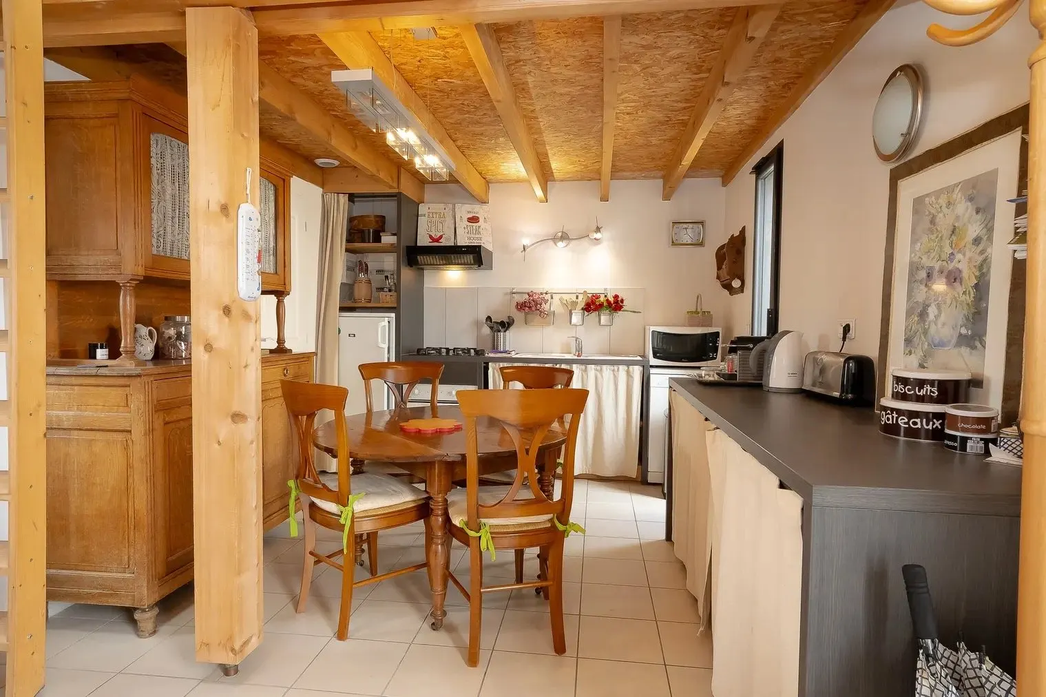 La cuisine équipée et la table en bois pour quatre sous les poutres