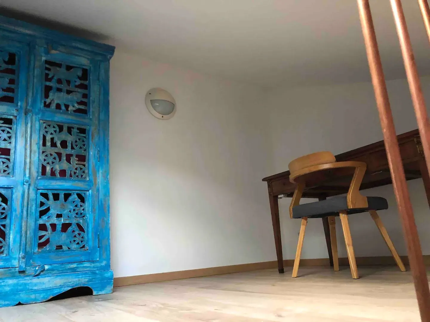 A carved blue wardrobe and a wooden desk, a quiet corner to work
