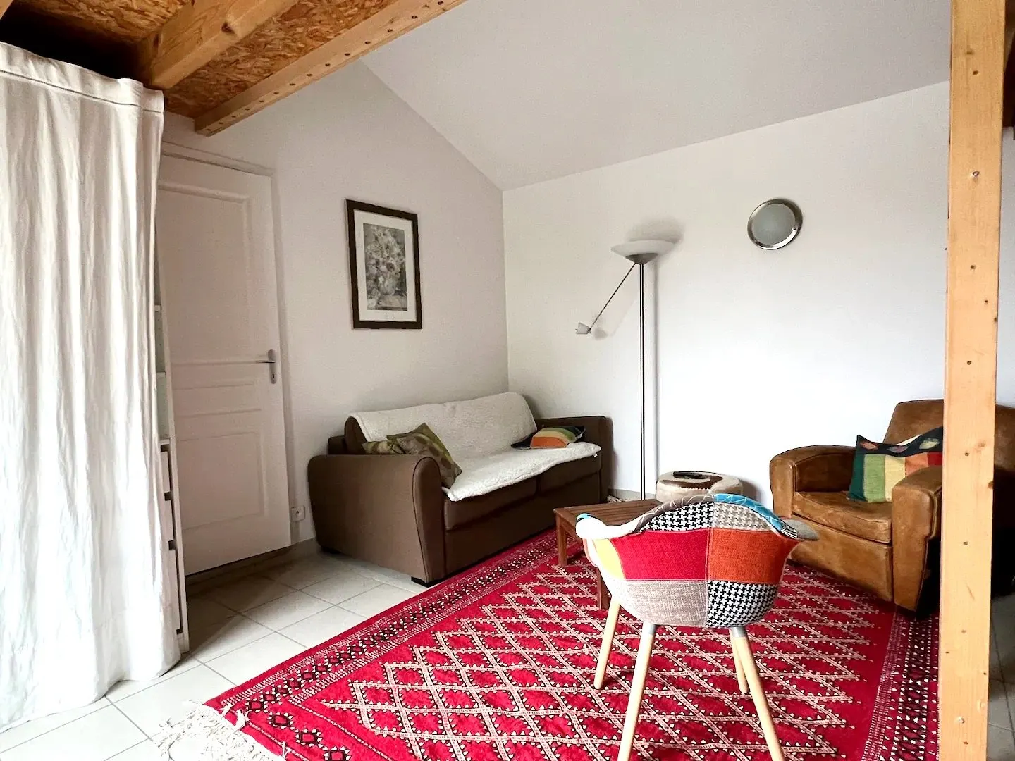 The living-room sofa bed with a red rug and colourful armchairs